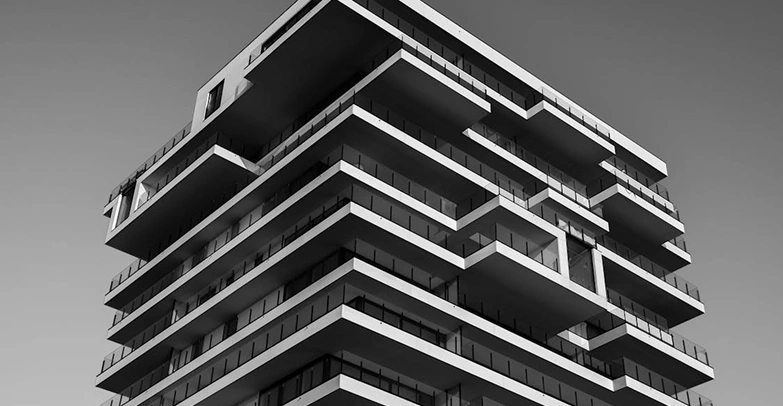 Hedendaags hoogbouwcomplex met balkons over meerdere verdiepingen, minimalistisch architectonisch ontwerp in zwart-wit.