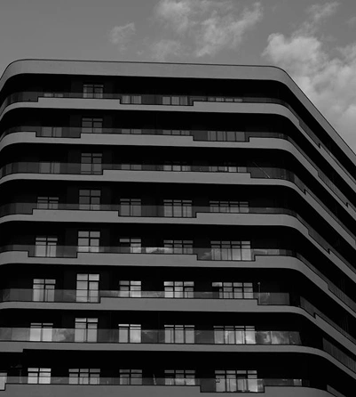 Modern gebouw met gebogen gevel en herhalende balkons, stijlvolle stedelijke architectuur in monochrome tinten.
