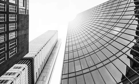 Gebogen glazen wolkenkrabber met reflectie van zonlicht, dynamische stedelijke architectuurcompositie in monochrome stijl.