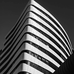 Gebogen, moderne kantoorgevel met horizontale lijnen, strak architectonisch ontwerp in zwart-wit.