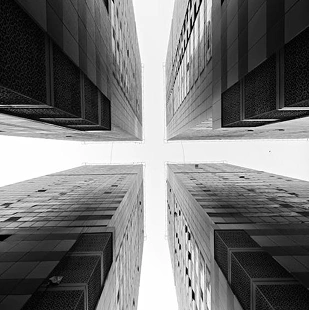Symmetrisch beeld van vier wolkenkrabbers die in een kruisvorm naar de hemel reiken, een dramatische compositie van stedelijke architectuur.