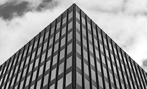 Symmetrisch perspectief van een kantoorgebouw met een rastergevel en een minimalistisch architectonisch patroon in monochrome tinten.