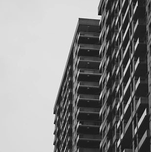 Perspectiefaanzicht van een hoog gebouw met herhalende ramen en balkons, minimalistische stedelijke architectuur.