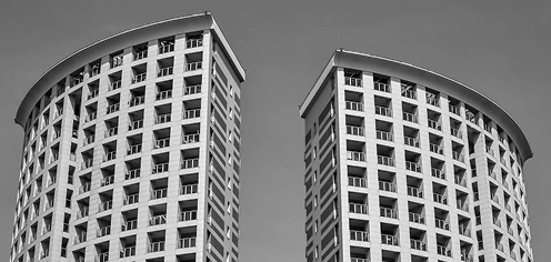 Twee ronde appartementengebouwen met herhalende balkons, moderne stedelijke woningbouwarchitectuur in zwart-wit.