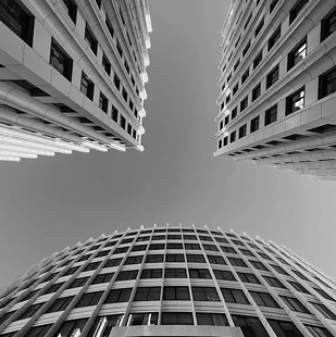 Bovenaanzicht van gebogen en rastervormige wolkenkrabbers die een geometrische compositie vormen, moderne stedelijke architectuur in zwart-wit.