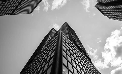 Verticaal zicht op een hoge wolkenkrabber die de lucht in rijst, moderne stadsarchitectuur in zwart-wit.