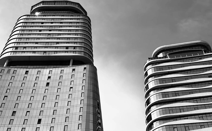 Twee moderne woontorens met afgeronde hoeken, eigentijdse hoogbouwarchitectuur in monochrome kleuren.